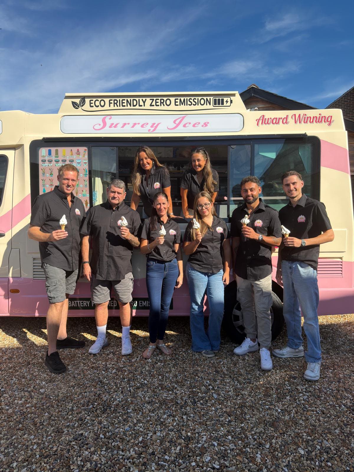 The Surrey Ices team holding soft serve cones in front of a cream and pink van