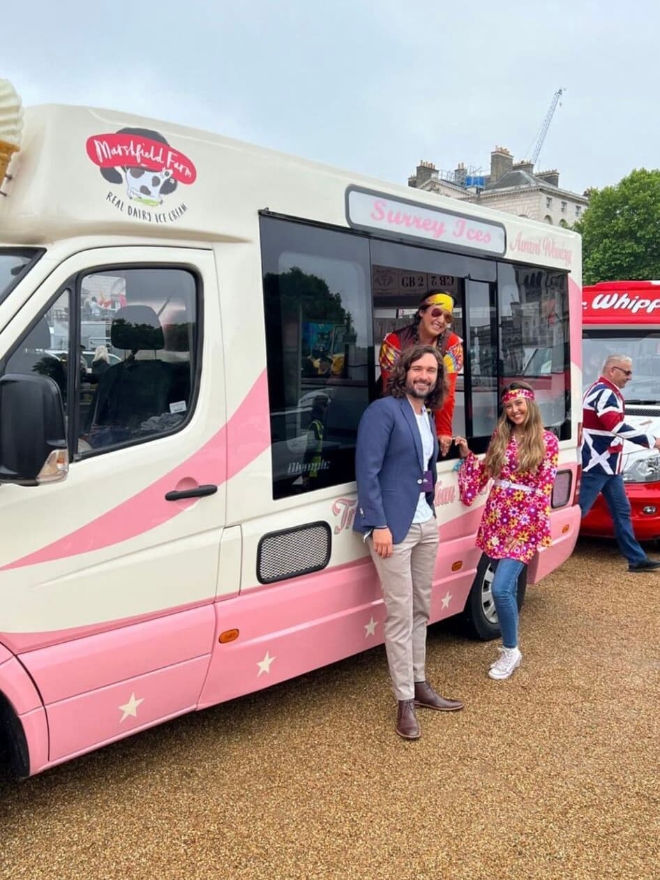 People standing beside a cream and pink Surrey Ices van, with a red Mr Whippy van behind them